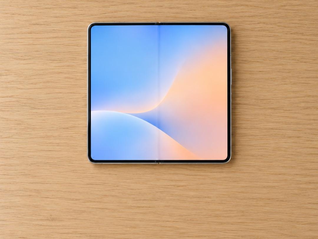 An unfolded foldable smartphone lying on a light oak table