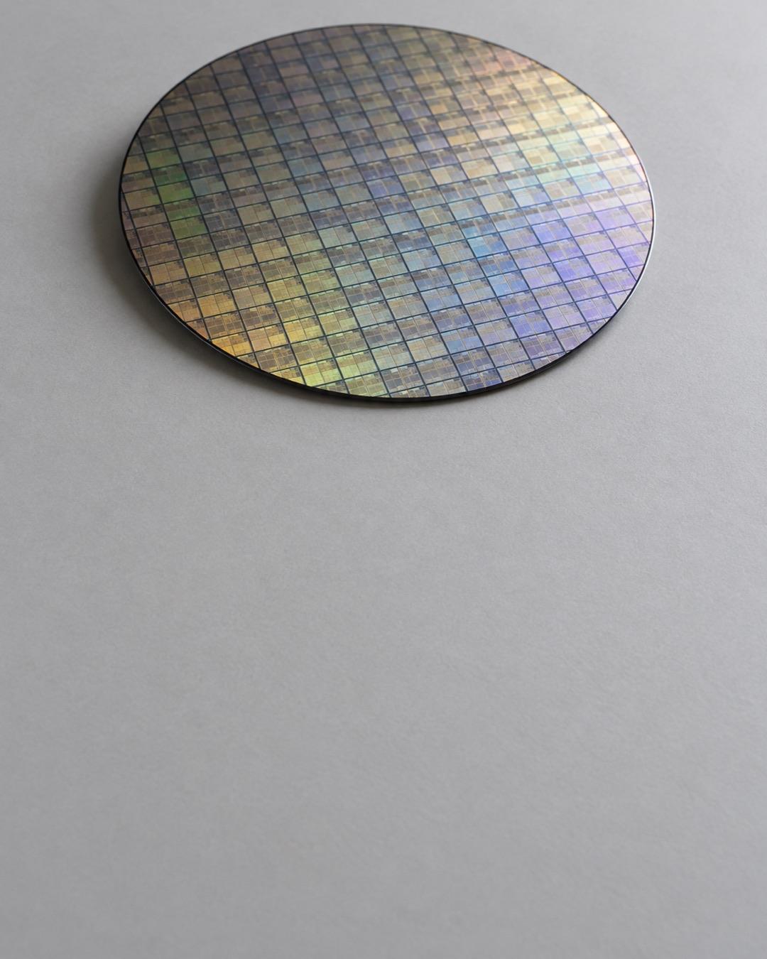 Polished silicon wafer with a grid of chip patterns on a light grey surface