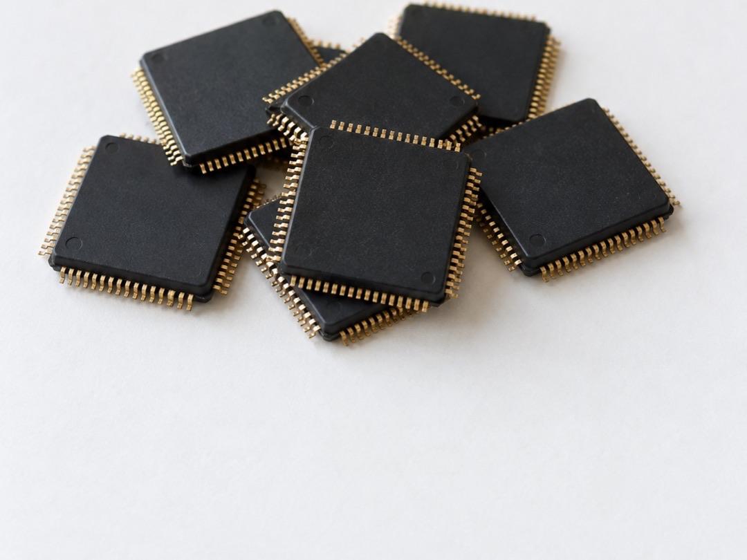 Small pile of black computer chips with gold contact pins on a white surface